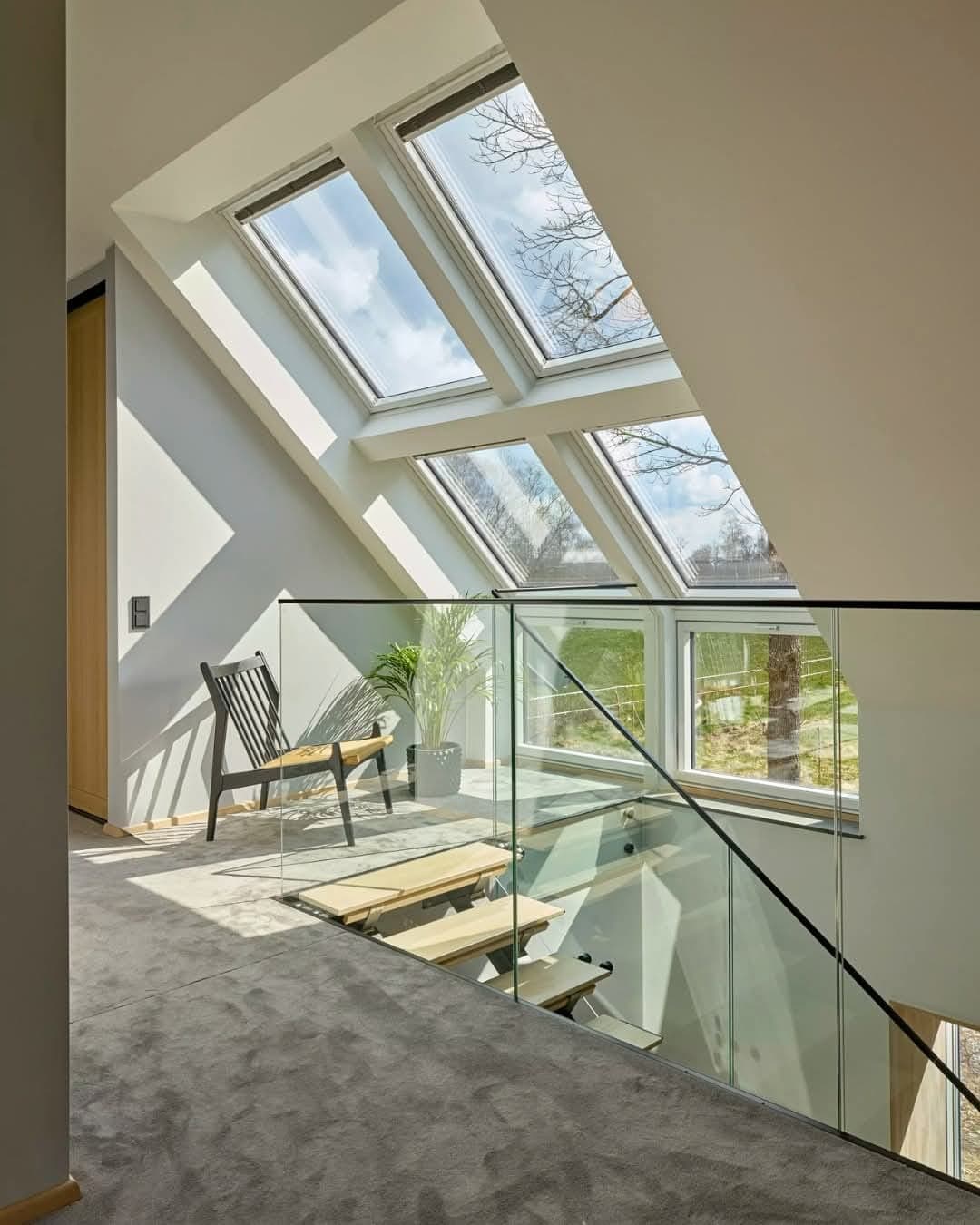 Finished loft interior with twin skylights, glass railing, and warm carpet