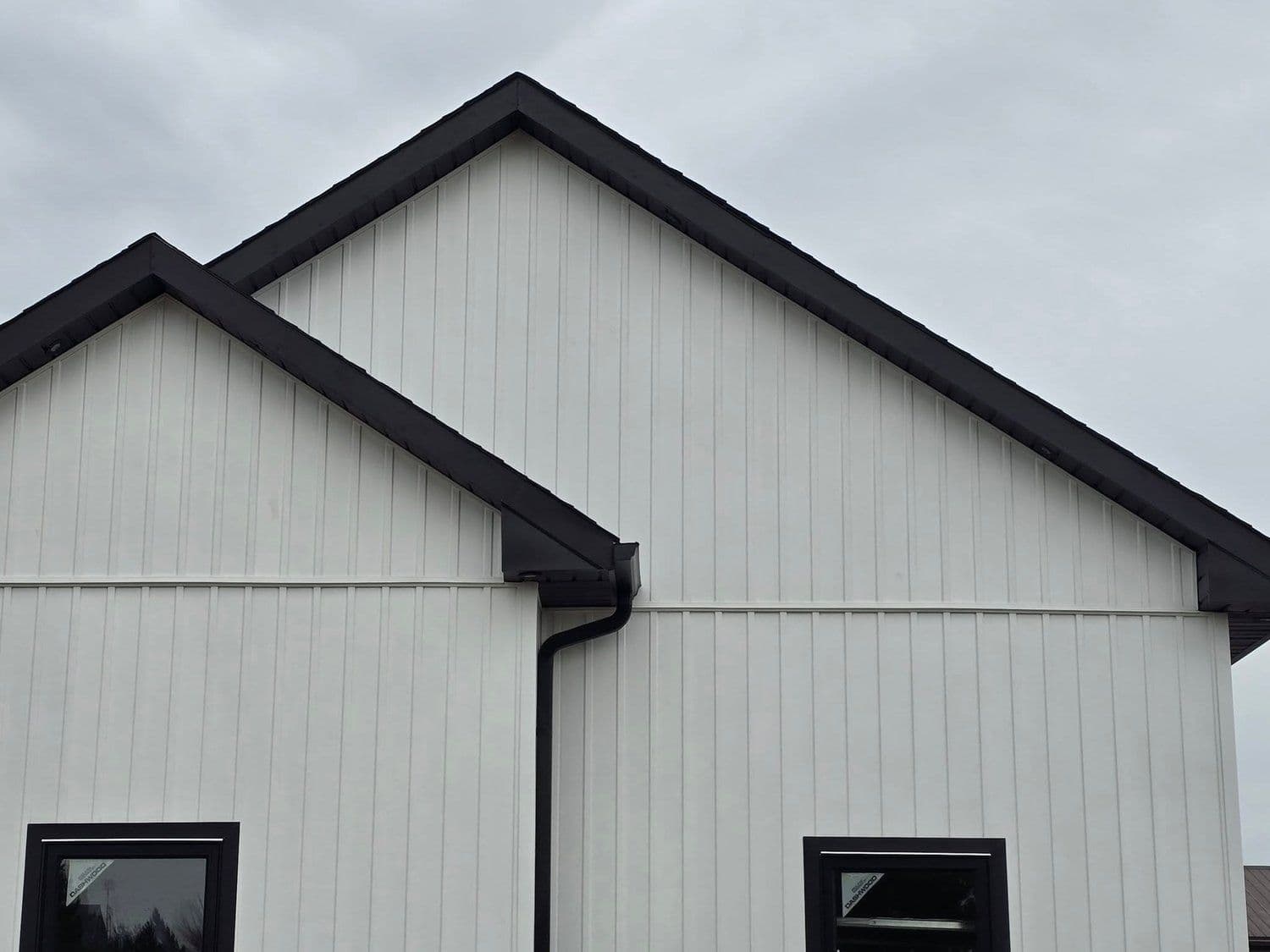 Modern farmhouse exterior with vertical white board-and-batten siding and black metal trim, recently completed by Elite Property Solutions in Hamilton